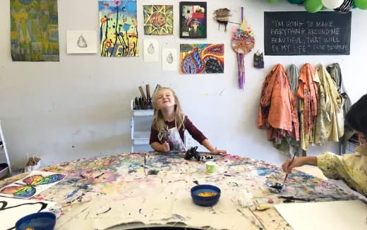 a person sitting on a blanket in a room with art on the wall