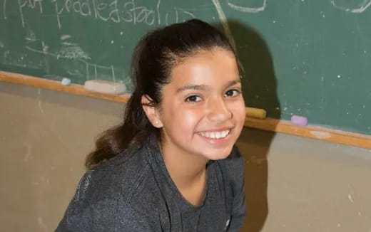 a girl smiling in front of a chalkboard