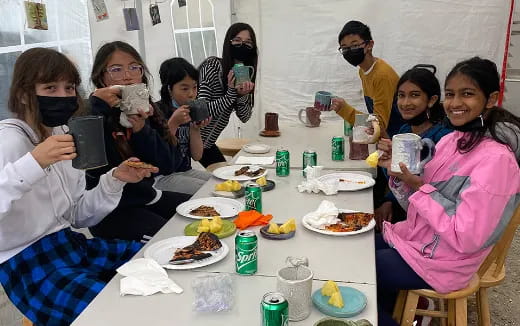 a group of people sitting around a table with food on it