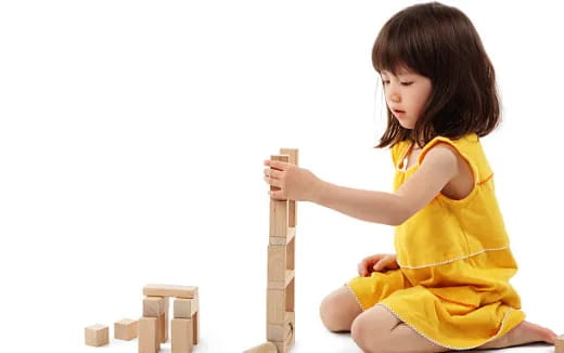 a young girl sitting on a stack of wood blocks