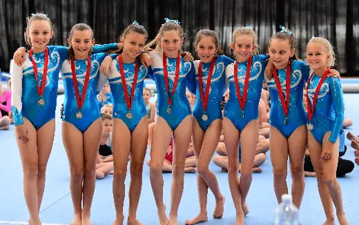 a group of girls wearing medals and standing in a pool