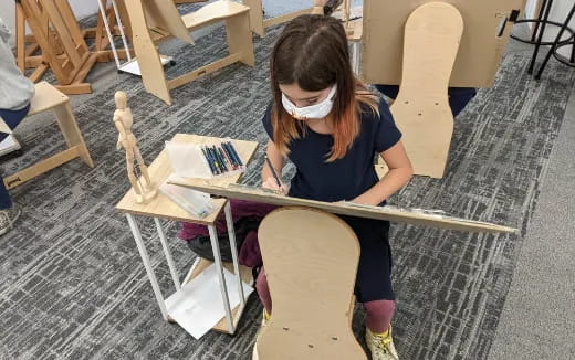 a girl sitting at a table with a sword and a book