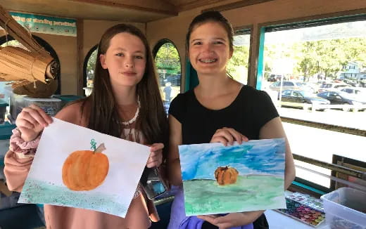 a couple of women holding a piece of paper with a picture of a fruit on it
