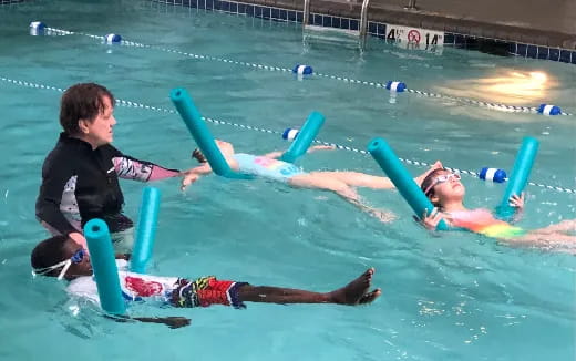 a man and a woman in a pool with a man in a swimsuit