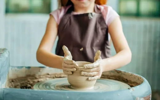 a woman making a clay pot