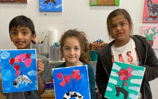 a group of children holding paintings