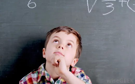 a boy with his hand on his chin in front of a chalkboard