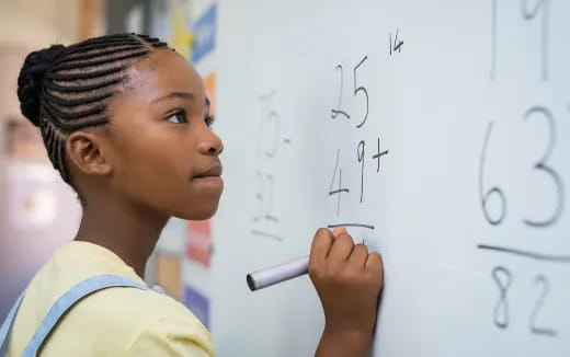 a young girl writing on a whiteboard