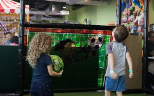 a couple of kids looking at a panda in a cage