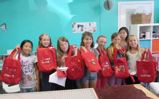 a group of girls holding red bags