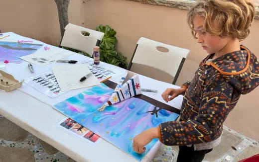 a child sitting at a table with a map and a book