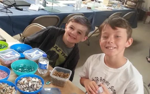 a couple of boys sitting at a table with food and drinks