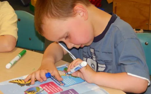 a young boy coloring on a paper