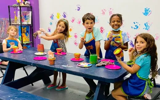 a group of children sitting at a table with food