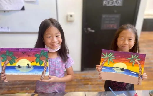 a couple of girls holding paintings