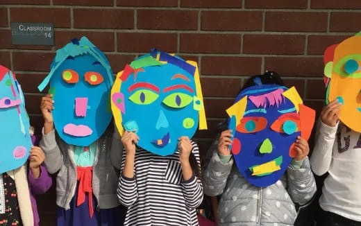 a group of children holding up colorful masks
