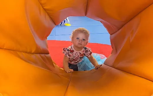 a baby in a large yellow and red slide