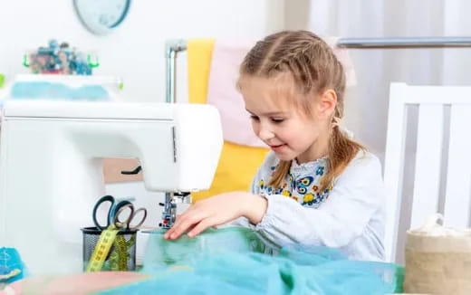 a little girl using a sewing machine