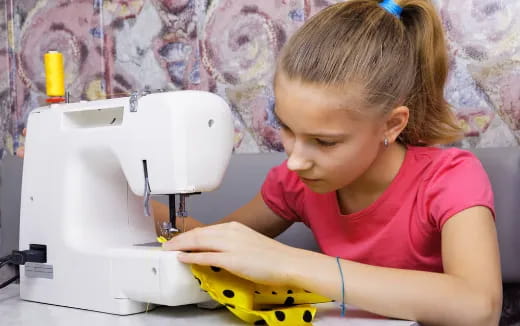 a young girl using a sewing machine