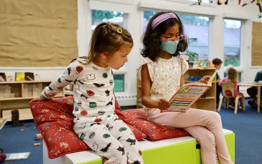 a person reading a book to a young girl