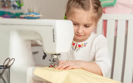 a girl sitting at a sewing machine