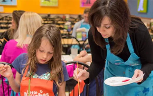 a person helping a young girl with a drawing