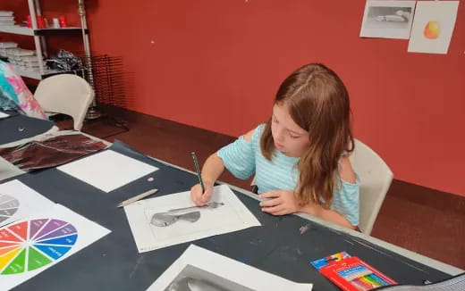 a girl sitting at a table writing on paper