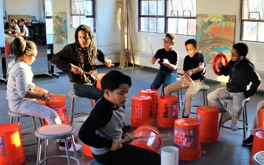 a group of people sitting around a table with red buckets