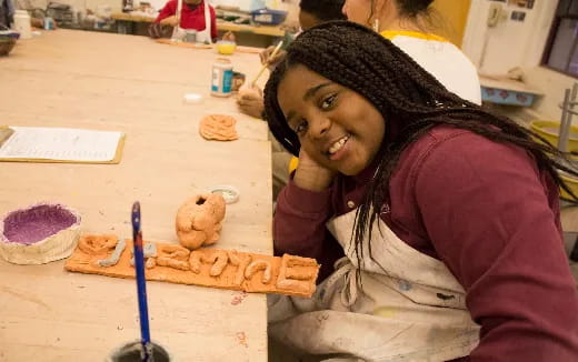 a woman smiling and leaning on a table with a cookie on it