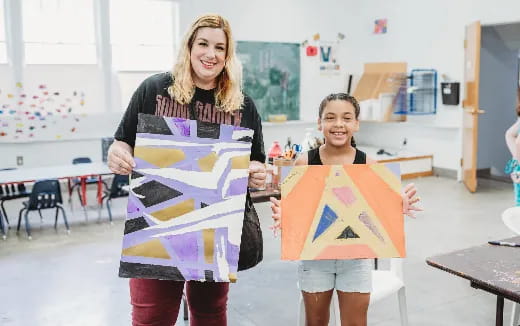 a woman and a boy holding a sign in a classroom