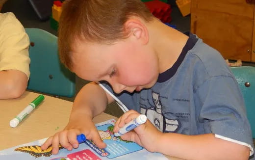 a young boy coloring on a paper