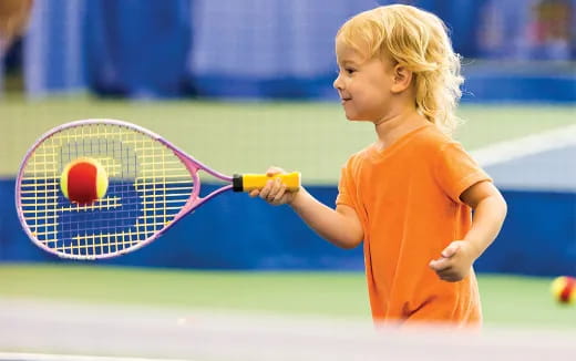 a little girl playing tennis