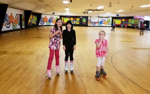 a group of girls wearing roller skates and standing in a bowling alley