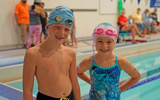 a boy and girl in swimsuits in a swimming pool