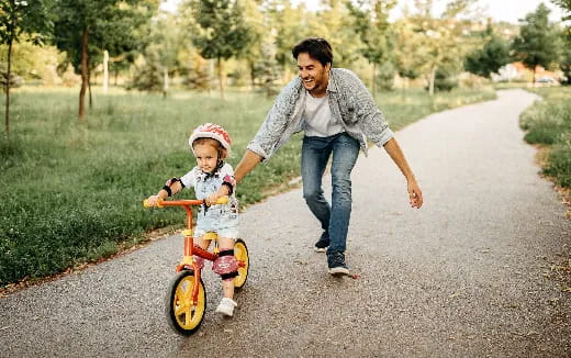 a man pushing a child on a bike