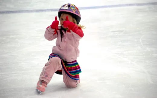 a child wearing a helmet and ice skates