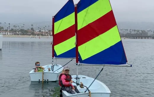a couple of people on a boat with a colorful sail