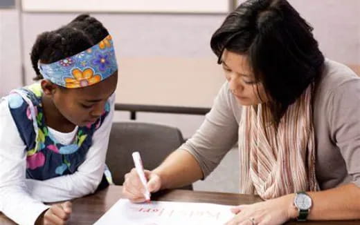 a person and a child writing on a piece of paper