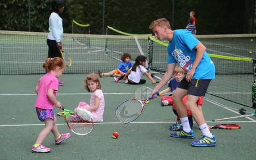 a person and kids playing tennis