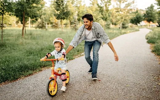 a man pushing a child on a tricycle