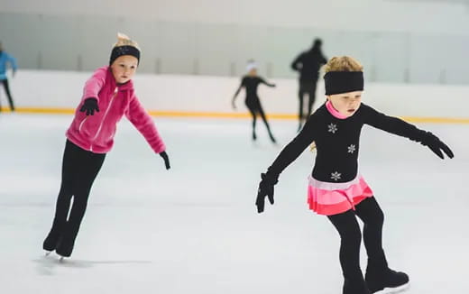 a couple of girls ice skating