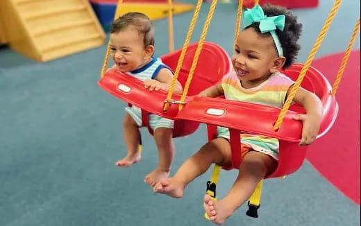 a couple of children playing on a swing