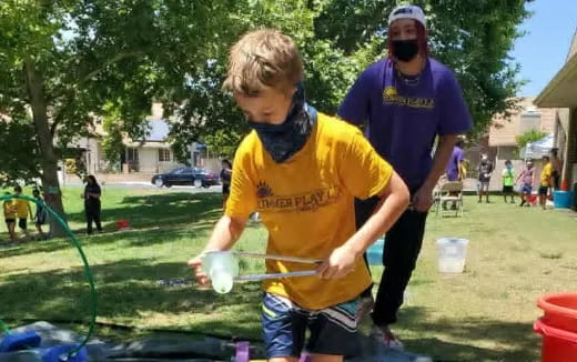 a person spraying a boy with a hose