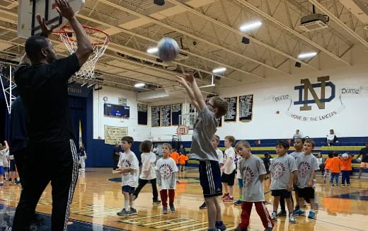 a person and a group of children in a gym