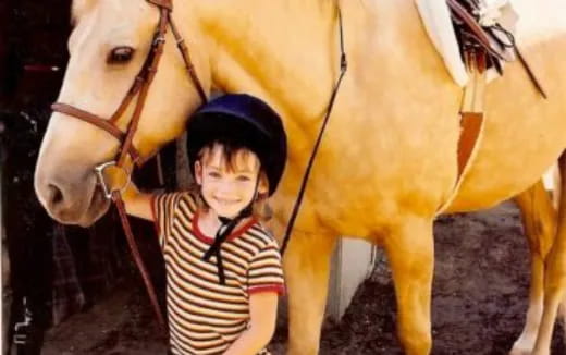 a boy standing next to a horse