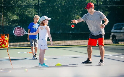 a person and a couple of kids playing tennis