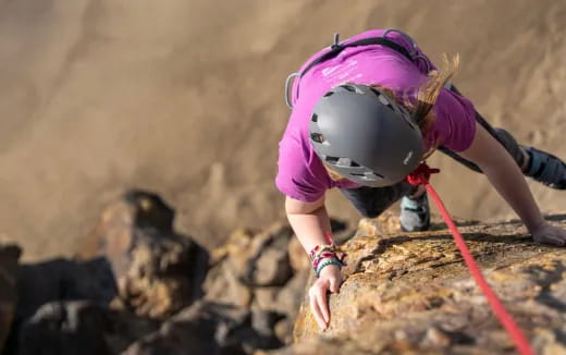 a person wearing a helmet and climbing a rock