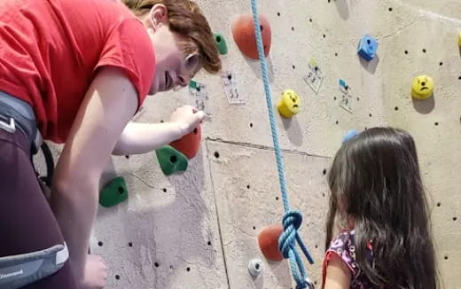 a person and a girl climbing a rock wall