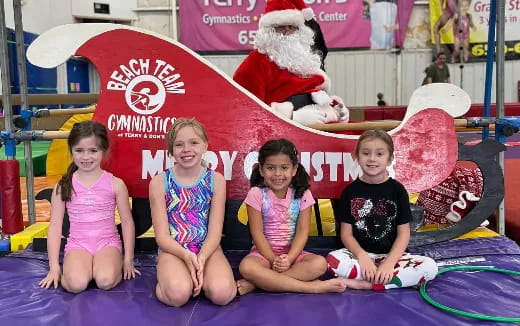 a group of children sitting on a mat in front of a santa claus
