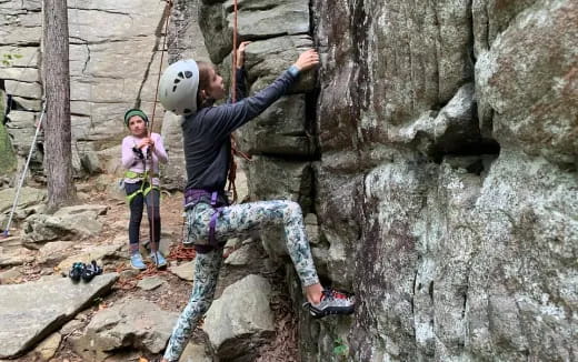 a man climbing a rock wall with a girl on a rope